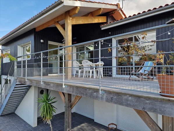 A modern house with a balcony, outdoor seating, and a staircase.