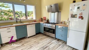A kitchen with a window, a stove, a refrigerator, and cabinets. - Beautiful architect-designed villa 30 m from the beach ☀️ (Andernos-les-Bains)