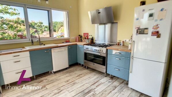 Una cocina con ventana, estufa, refrigerador y armarios.