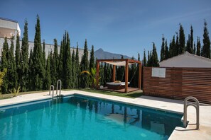 Een buitenzwembad en ligstoelen