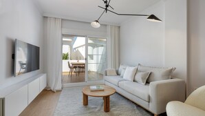 A modern living room with a sofa, a coffee table, a TV, and a ceiling light fixture. - RDR254 - Stunning 1 bedroom Apt. Golden Banús! (Marbella)
