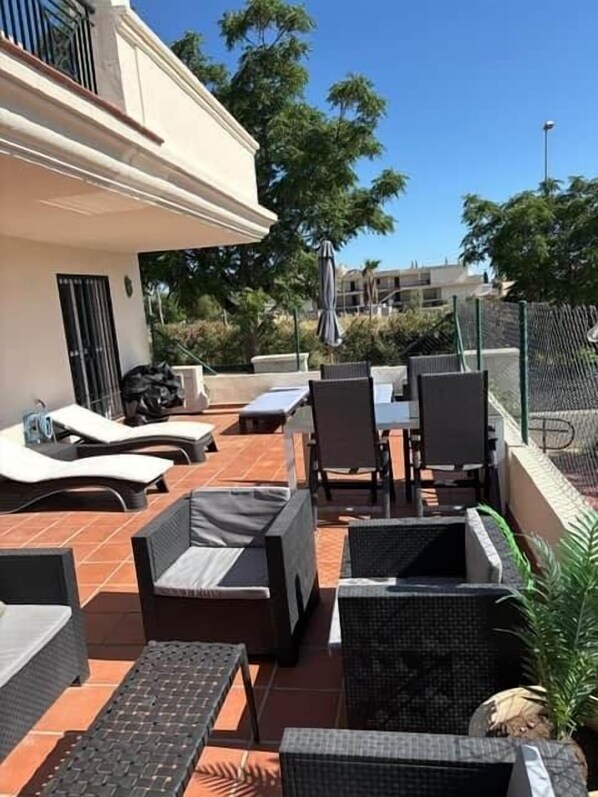 An outdoor patio with wicker furniture, a table, and chairs.