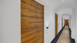 Un couloir avec des portes en bois et un sol carrelé de noir et de beige.