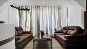 Un salon avec deux canapés en cuir marron, une table basse en verre et un vase rempli de fleurs.