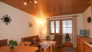A cozy living room with a wooden ceiling, a sofa, a dining table, and a television. - Obersee. Apartments Klausner (Schönau am Königssee)
