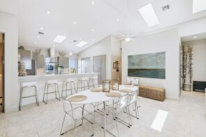 A modern kitchen with a central island, bar stools, and a dining table with placemats.