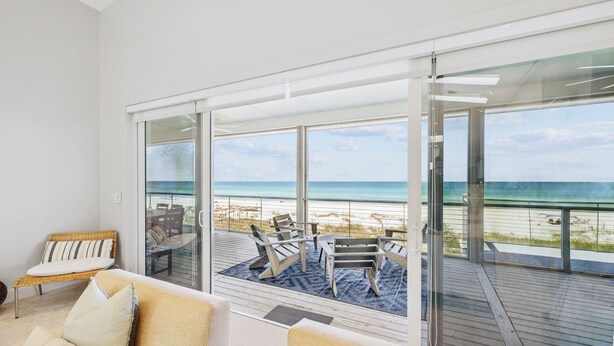 Ein modernes Zimmer mit einer großen Schiebeglastür, die auf einen Balkon mit Blick auf den Strand führt.