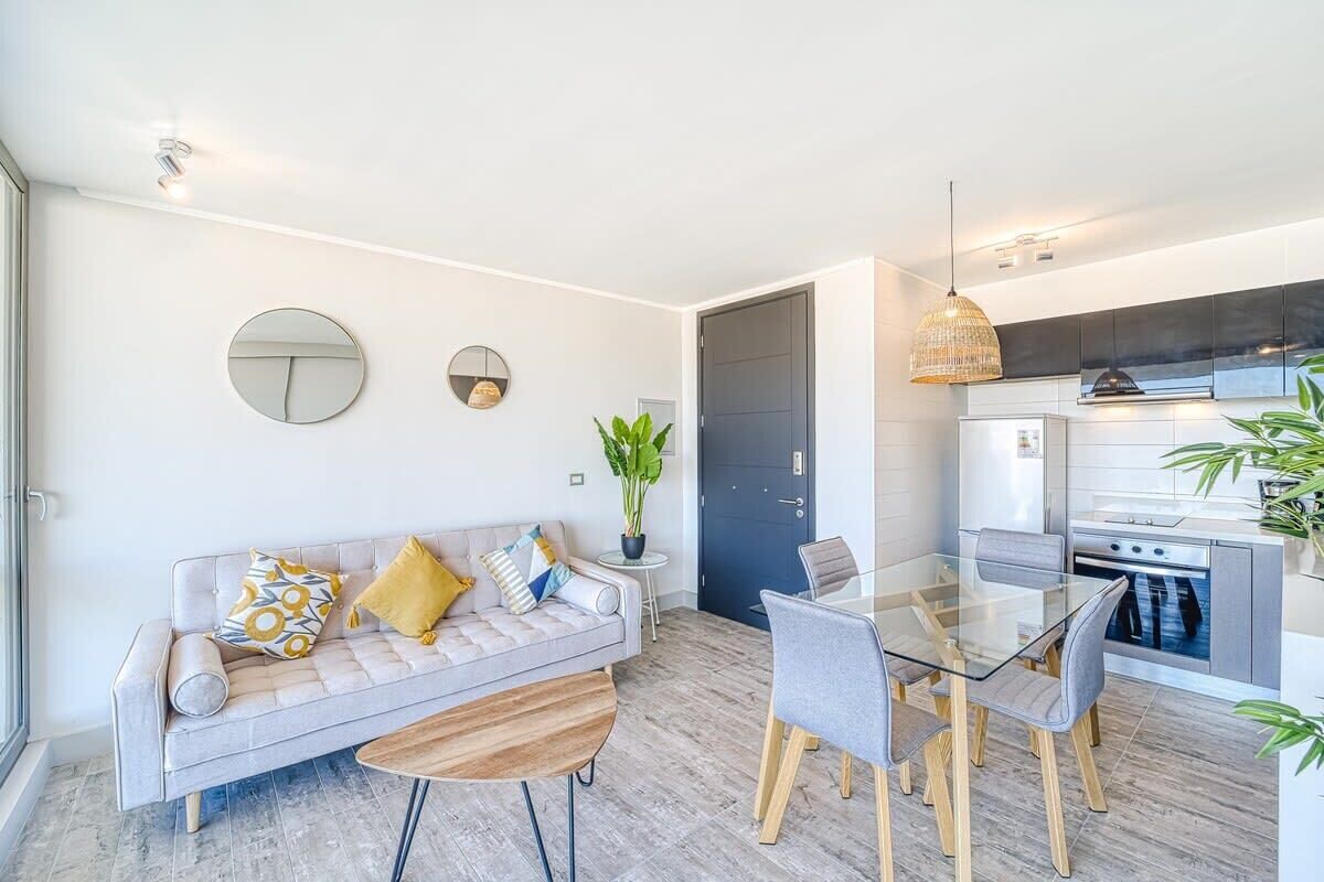 Un salon moderne comprenant un canapé, une table basse et une table à manger. Il y a également un coin cuisine avec une cuisinière et des placards.