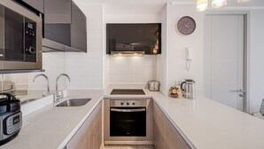 A compact kitchen with a microwave, oven, sink, and a toaster. - Galerna Home 2BR W/Balcony, Wifi & Parking. (Concón)