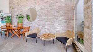 A modern indoor seating area with a brick wall, wooden furniture, and potted plants. - Wood Summer 2B W/Parking, Wifi & View. (Viña del Mar)