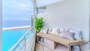 A balcony with a wooden bench, cushions, and a potted plant. - Bay Dream 2B W/Wifi, Grill & View. (Algarrobo)
