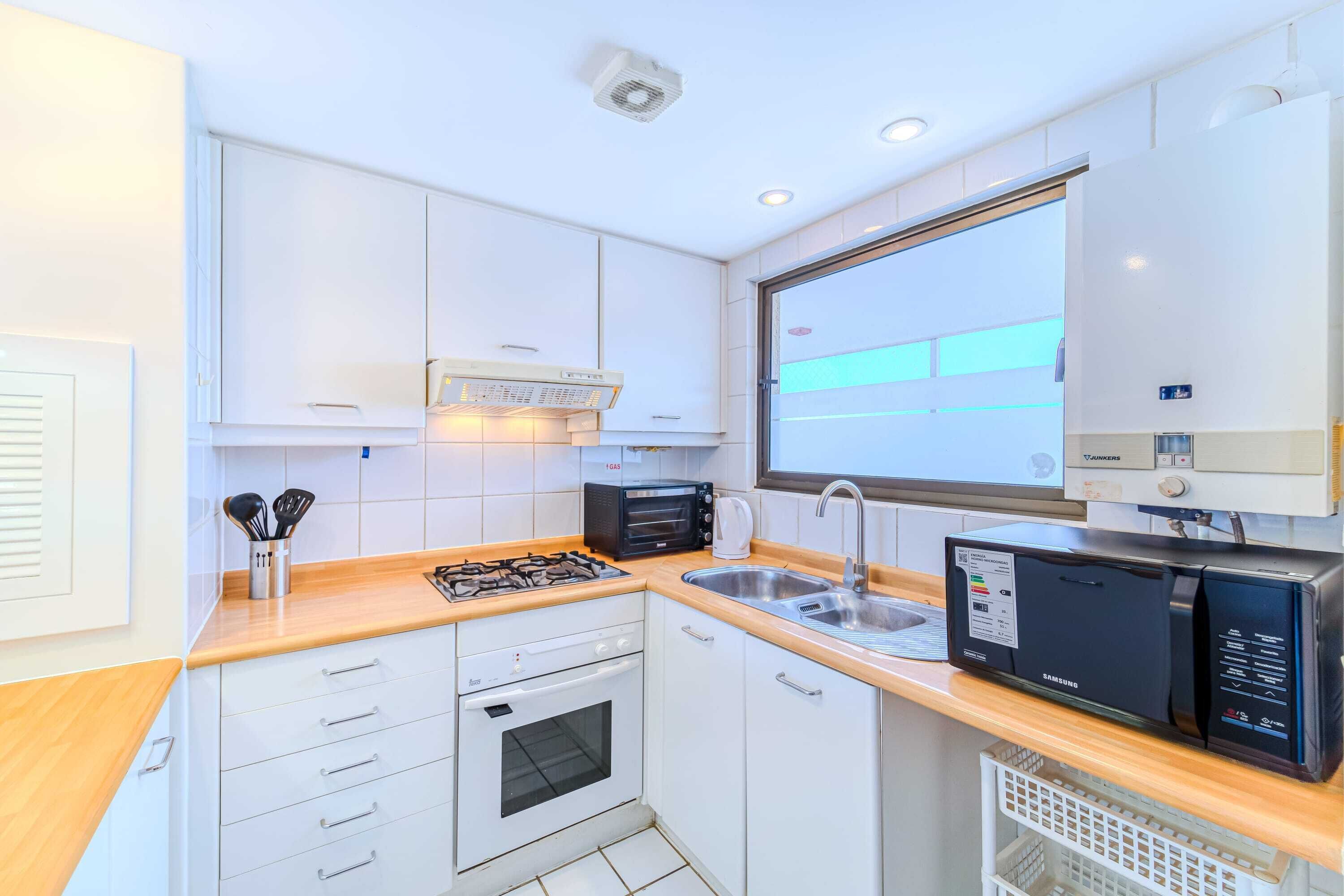 A modern kitchen with white cabinets, a microwave, a toaster, and a sink.