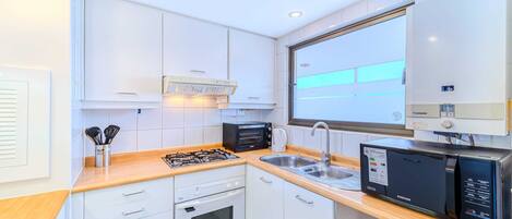 A modern kitchen with white cabinets, a microwave, a toaster, and a sink.