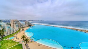 A coastal resort with multiple swimming pools, a beach, and a view of the ocean. - Bay Dream 2B W/Wifi, Grill & View. (Algarrobo)