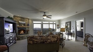 A living room with a fireplace, a television, and a large window with a view. - Unbeatable views at 5,200 ft and walking distance to slopes. (Sugar Mountain)