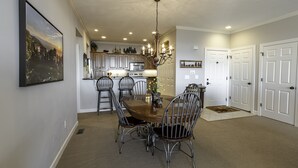 A dining area with a wooden table and metal chairs, a chandelier, and a kitchen in the background. - Unbeatable views at 5,200 ft and walking distance to slopes. (Sugar Mountain)