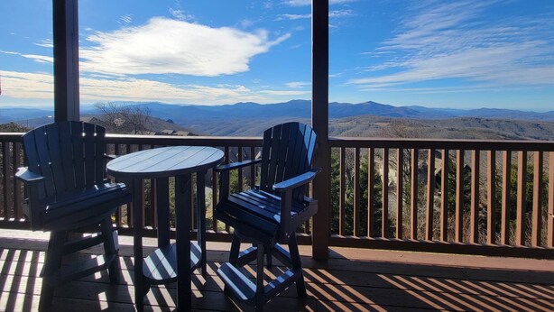 A covered outdoor area with a table and two chairs, overlooking a mountainous landscape. - Unbeatable views at 5,200 ft and walking distance to slopes. (Sugar Mountain)