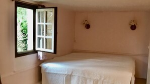 Une chambre à coucher avec un lit, une chaise, une fenêtre et un luminaire fixé au mur.