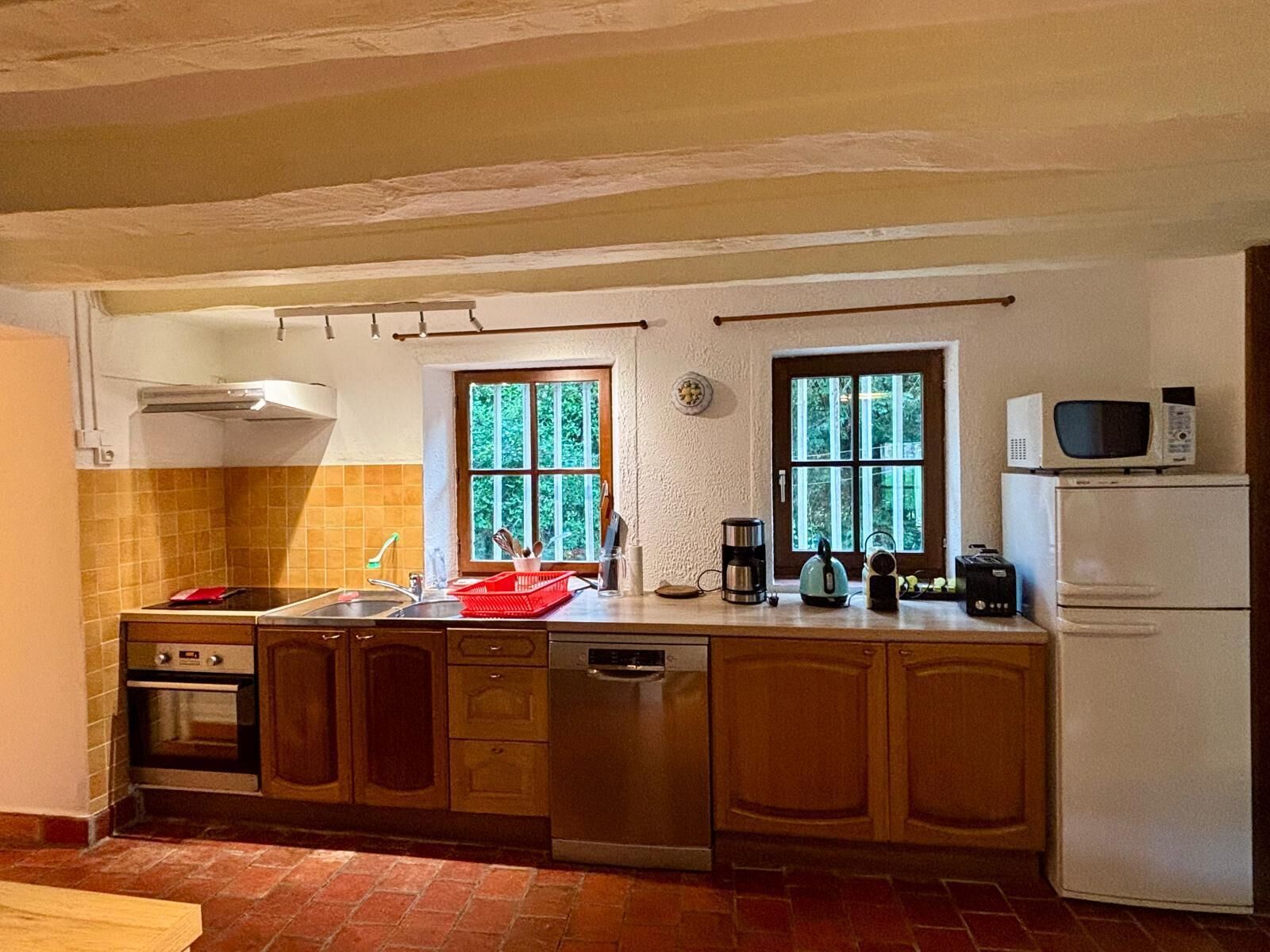 A kitchen with a sink, stove, dishwasher, and a microwave on the countertop.
