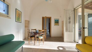 A dining area with a table and chairs, a sofa, and a sliding glass door leading to an outdoor area. - 1755 Casina Farnarari - Appartamento 1 by Barbarhouse (Monteroni di Lecce)