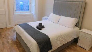 A bedroom with a bed, a nightstand, a window, and a door.
