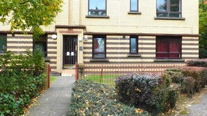 A multi-story residential building with a brick facade, multiple windows, and a gated entrance. - Charming  2 bed apt close to City and SEC/Hydro (Glasgow)
