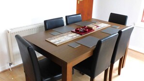 A dining table with six chairs, a wooden door, and a radiator. - Charming  2 bed apt close to City and SEC/Hydro (Glasgow)