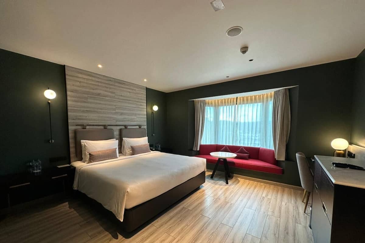 Ein modernes Hotelzimmer mit einem großen Bett, einer kleinen Sitzecke und einem Schreibtisch.
