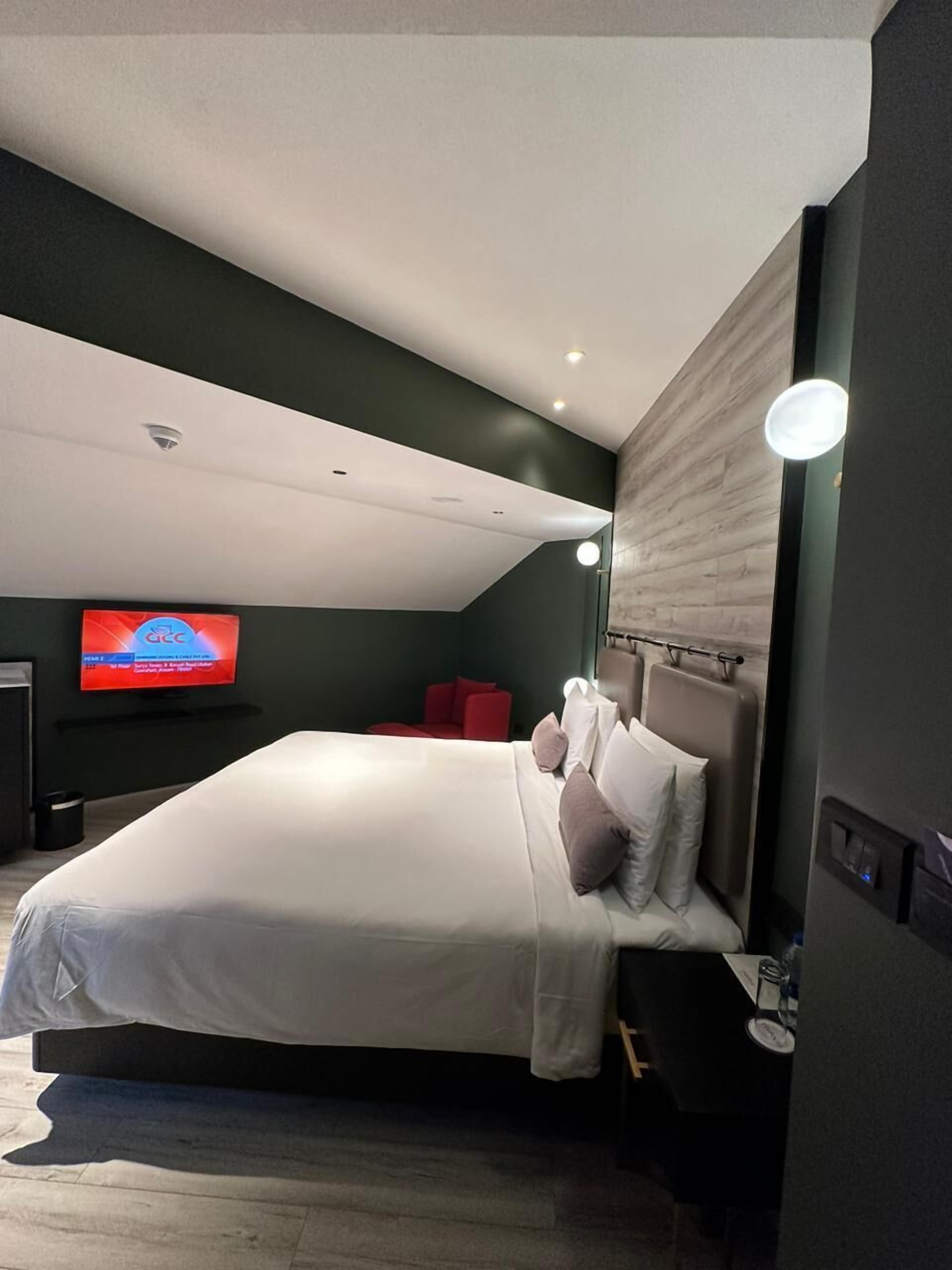 Un dormitorio moderno con una cama grande, un televisor en la pared y una silla roja.
