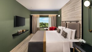 Een moderne hotelkamer met een groot bed, een flatscreen televisie, een klein tafeltje en uitzicht op het landschap.