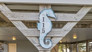A wooden structure with a seahorse-shaped number sign '115' mounted on it.