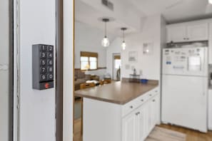 Una cocina moderna con armarios blancos, una encimera de madera y un refrigerador empotrado.