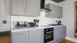 A modern kitchen with grey cabinets, a white tiled backsplash, and stainless steel appliances. - Bateman, modern City centre apartment sleeps 6 (York)