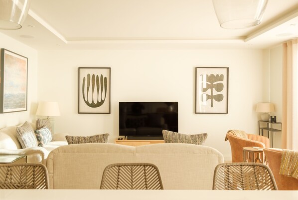 A modern living room with a flat-screen TV, two framed abstract artworks, a sofa, and a coffee table.