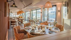 A dining area with round tables, wicker chairs, and hanging pendant lights.