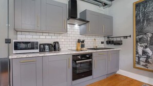 Una cocina moderna con gabinetes grises, horno empotrado, microondas y cafetera.