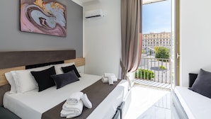 Ein modernes Hotelzimmer mit Bett, einem Gemälde, einer Klimaanlage und einem Balkon mit Blick auf die Stadt.