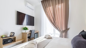 Ein Hotelzimmer mit einem Bett, einem Schreibtisch, einem Fernseher und einem Fenster mit Vorhängen.