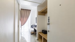 Ein modernes Hotelzimmer mit Bett, Schreibtisch und einem kleinen Holzregal mit einem Radio.