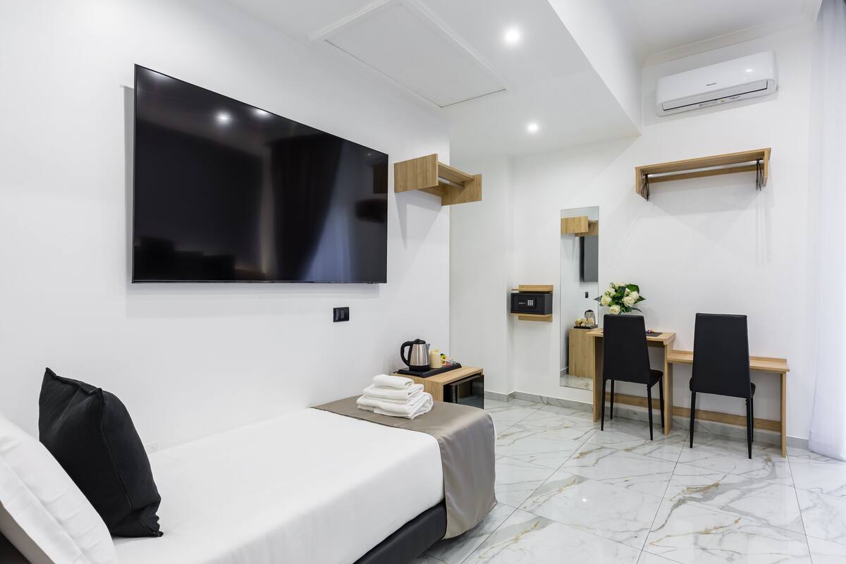 Une chambre d’hôtel moderne équipée d’un lit, d’un bureau, d’une chaise, d’une télévision et d’un appareil de climatisation.