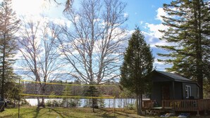 Takapihalla on lentopalloverkko, pieni mökki ja taustalla näkyy järvi.