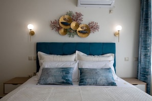 A bed with a teal headboard, white and blue pillows, and a wall decoration of shells and coral. - Apartment with Sea View (Kalamata)