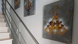 A staircase with a metal railing, leading to a landing where three artworks are displayed.