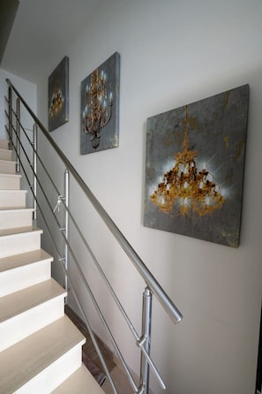 A staircase with a metal railing, leading to a landing where three artworks are displayed. - Apartment with Sea View (Kalamata)