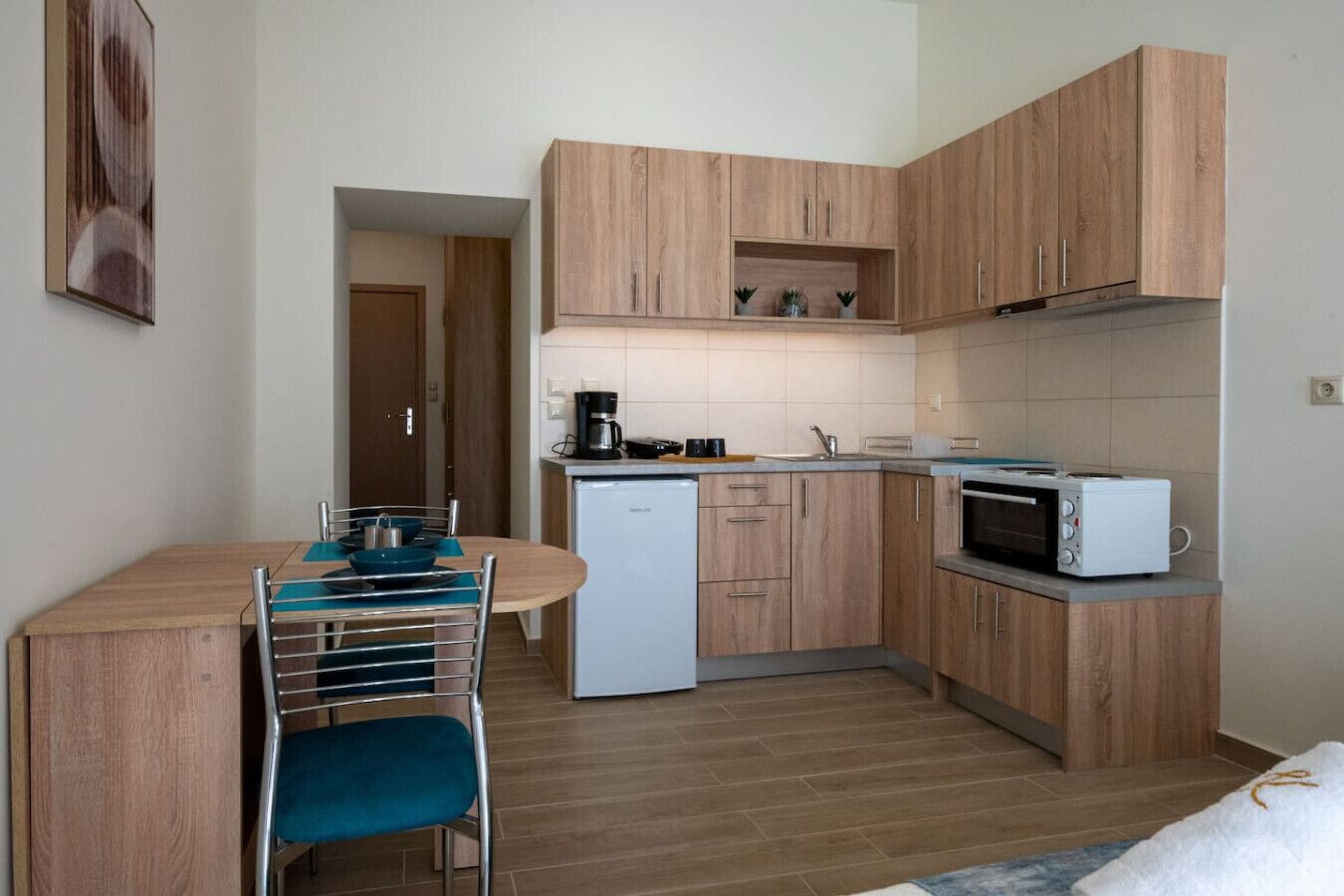 A compact kitchen with wooden cabinets, a microwave, a coffee maker, and a sink.