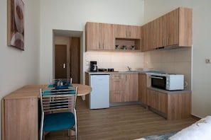 A compact kitchen with wooden cabinets, a microwave, a coffee maker, and a sink. - Apartment with Sea View (Kalamata)