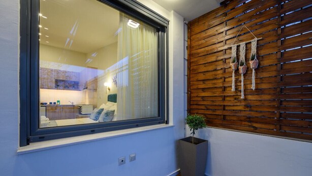 A modern interior with a large window, wooden wall paneling, and a potted plant.
