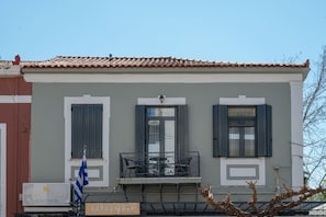 A building with three windows, a balcony, and a flag. - Apartment with Sea View (Kalamata)