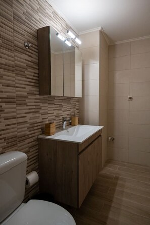 A modern bathroom with a wooden vanity, a white sink, and a large mirror.