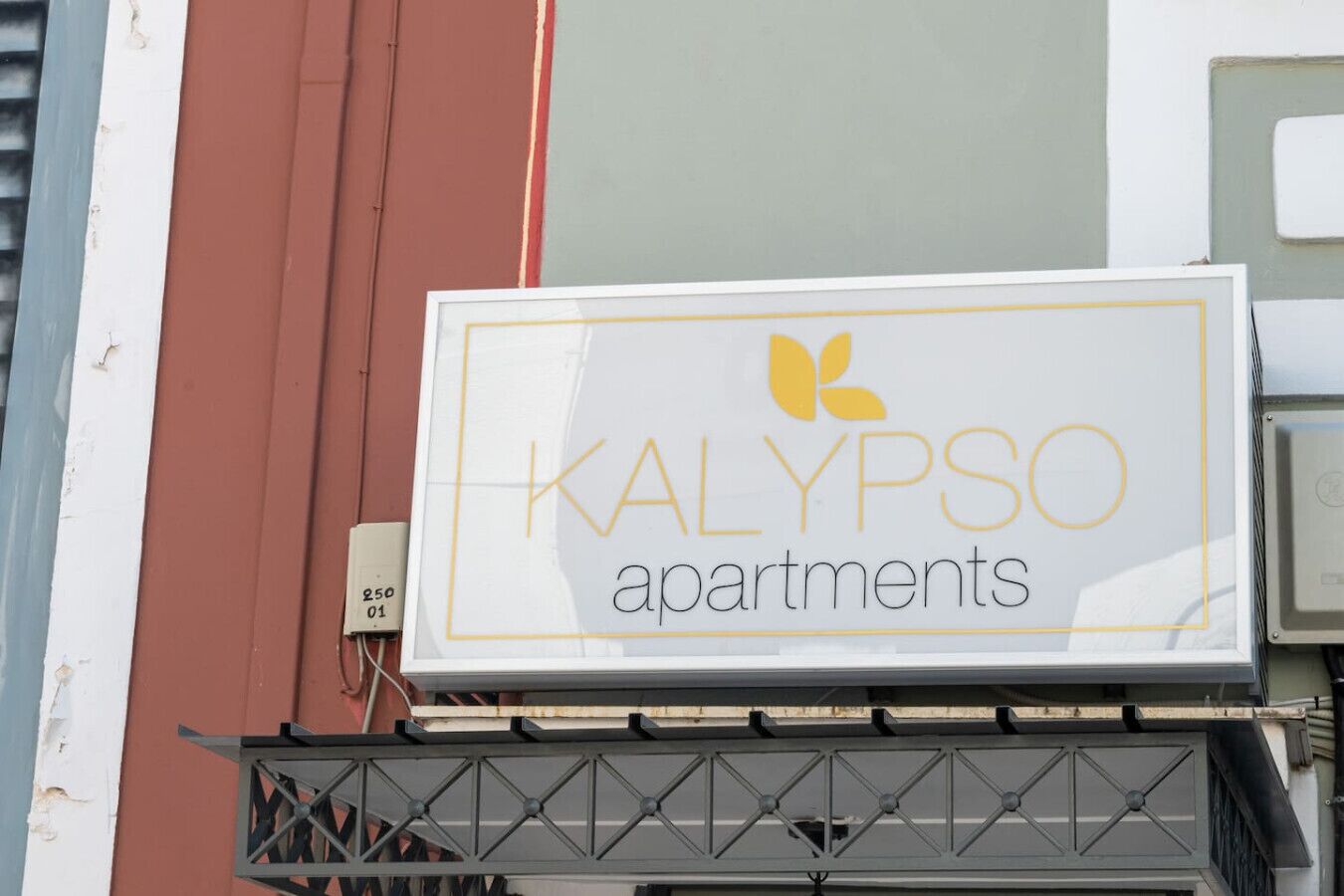 A sign for KALYPSO apartments with a yellow logo and text.